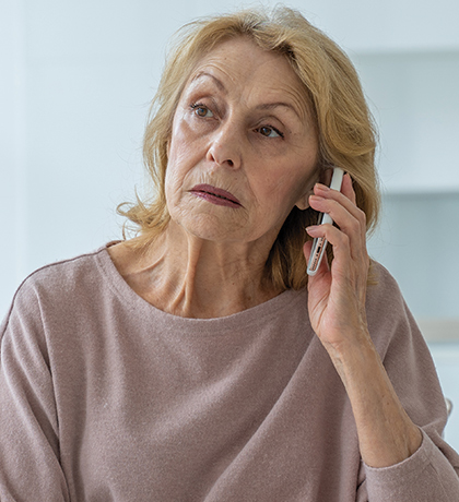 Photo of a woman on the phone wearing a dusty pink top