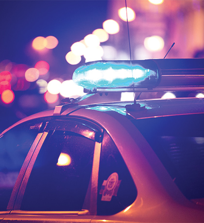 Photo of a police car with blue lights flashing at night