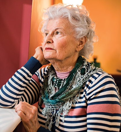 Photo of a woman with a striped top staring out a window