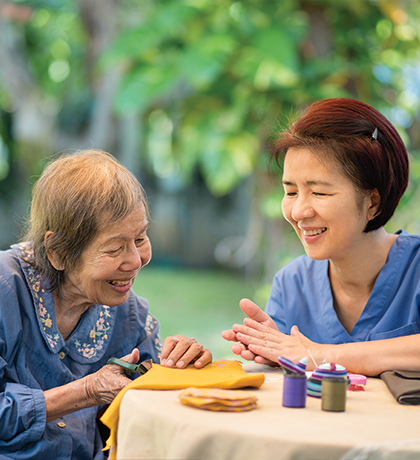 Photo of two women crafting at a table outdoors