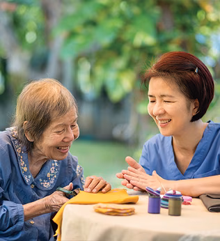 Photo of two women crafting at a table outdoors