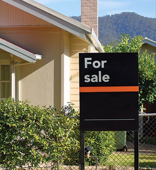 Photo of a For Sale sign in front of a house