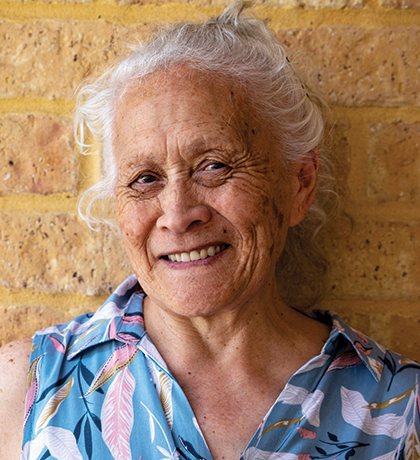 Photo of a smiling woman with a cream brick wall in the background