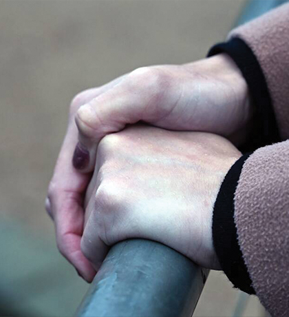 Photo of hands clasped over a metal handrail