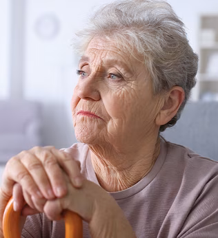 Photo of a woman with hands clasped over a walking stick