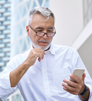 Photo of a man with a white beard and shirt looking at his phone