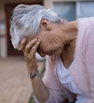 Photo of a woman in a pale pink cardigan with her head in her hand
