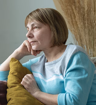 Photo of a woman amongst cushions resting her chin on her hand