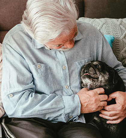 Photo of a man with a black pug dog