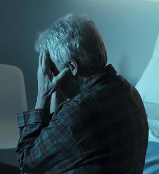 Photo of a person sitting in a dim room with head in hands