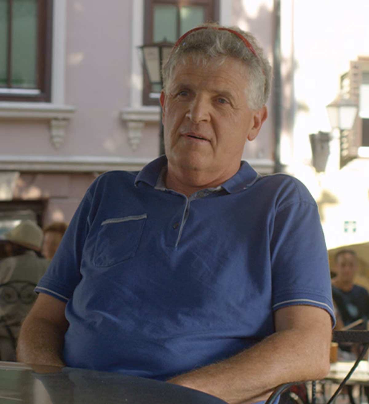 Photo of two men sitting under a tree at a cafe table