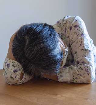 Photo of a person with their head on a table