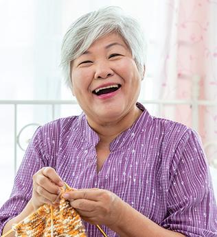 Photo of happy lady in a purple shirt knitting