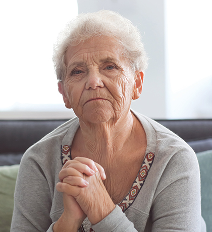 Photo of a woman in a grey top with hands clasped