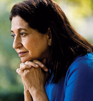 Photo of a woman in a royal blue shirt with chin on hands