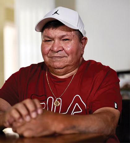Photo of person in a maroon tee shirt with a white ball cap