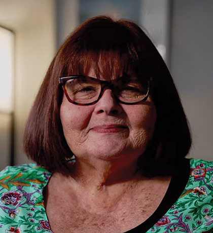 Photo of a woman in a paisley teal top in a cosy room