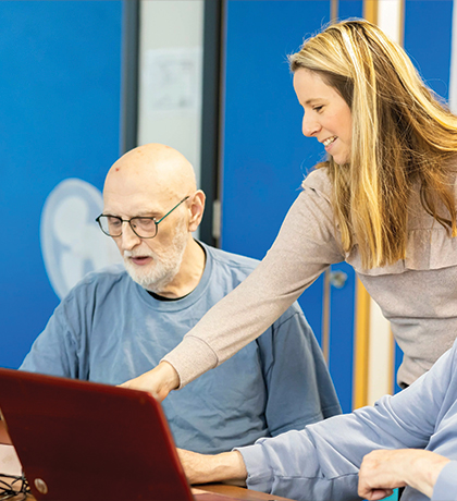 Photo of a woman helping two men with laptops