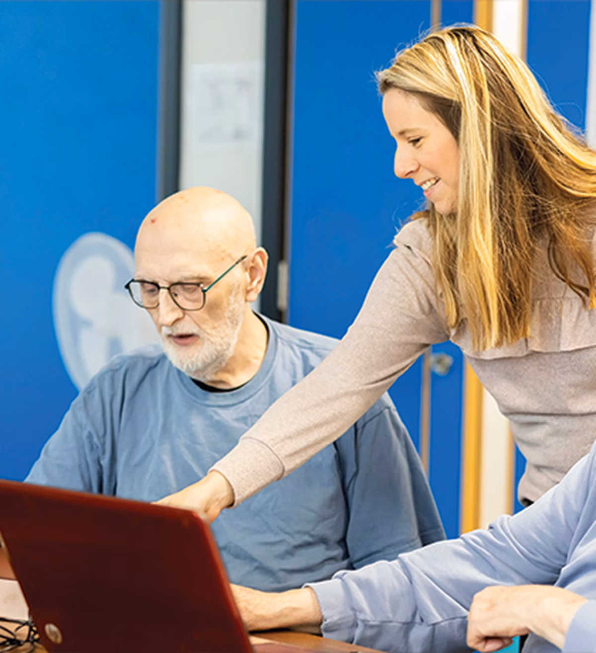Photo of a woman helping two men with laptops