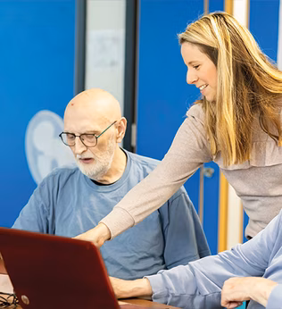 Photo of a woman helping two men with laptops