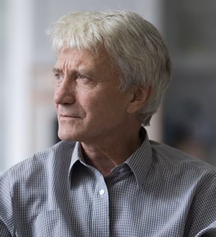Photo of a man with white hair and a grey check shirt