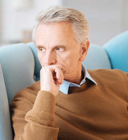 Photo of a man in a tan jumper in a blue armchair
