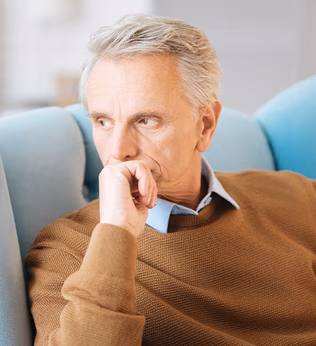 Photo of a man in a tan jumper in a blue armchair