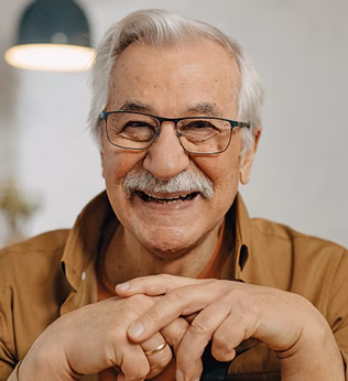 Photo of a man laughing in a brown shirt