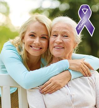 Photo of a woman in a blue cardigan embracing another woman on a park bench