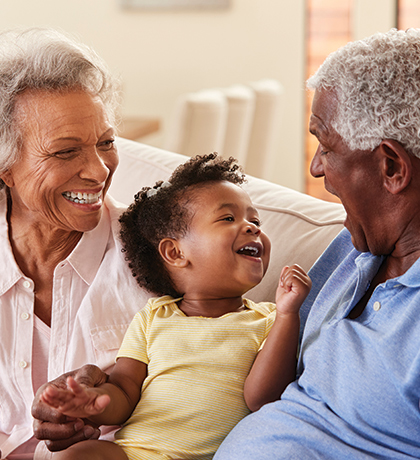 Photo of a laughing toddler sitting between two older people