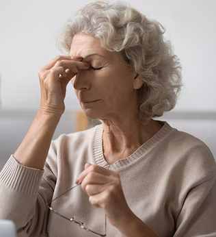 Woman in a beige jumper pinching the bridge of her nose