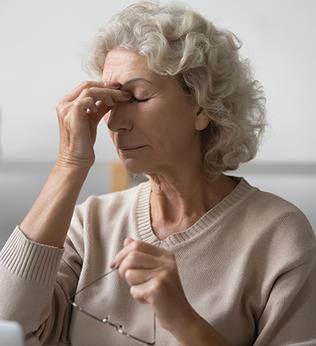 Woman in a beige jumper pinching the bridge of her nose