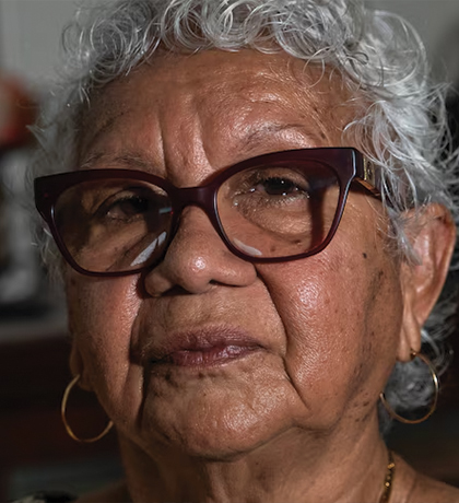 Photo of a woman wearing dark red glasses and gold hoops