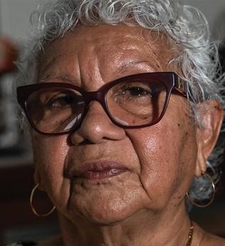 Photo of a woman wearing dark red glasses and gold hoops