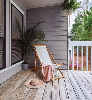 Photo of a deckchair, pink throw, and straw hat on a deck