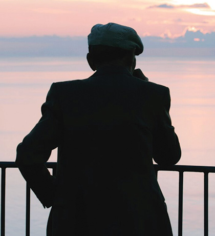 Photo of a man in a cap silhouetted against a sunset