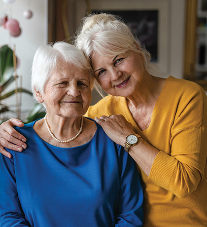 Photo of two smiling women with a vase of pink flowers