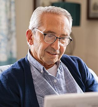 Photo of a man in a blue outfit reading the paper on a couch