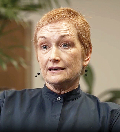 Photo of a woman with a ginger pixie cut and black shirt