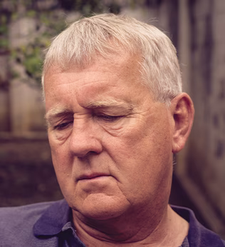 Photo of man in a courtyard wearing a purple polo shirt