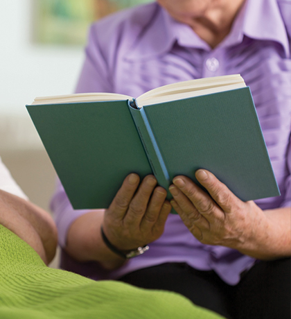 Photo of someone reading a book to a person in bed