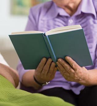 Photo of someone reading a book to a person in bed