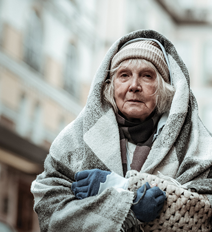 Photo of an older woman wrapped in blankets and woolllens