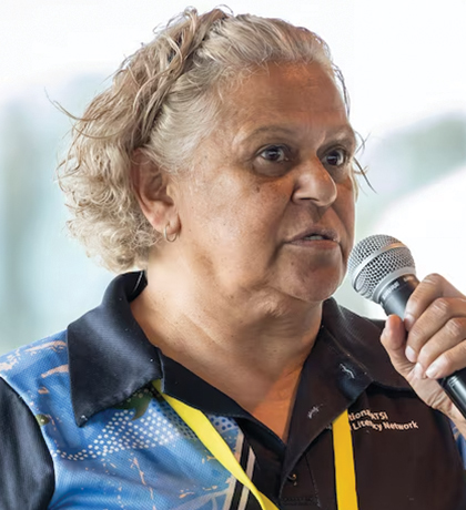 Photo of a woman with a yellow lanyard speaking into a microphone
