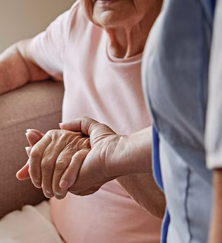 Photo of a nurse holding a seated woman's hand