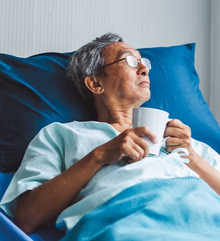 Photo of a man with a cup in a hospital bed