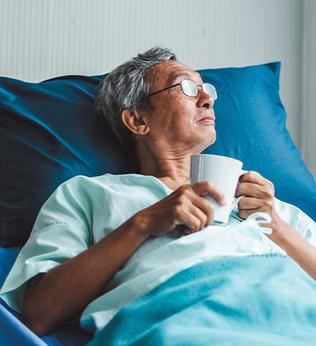 Photo of a man with a cup in a hospital bed