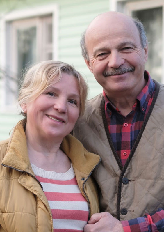 Senior couple standing outside of a house