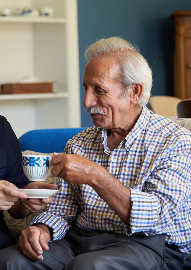 Carer with elderly man drinking coffee