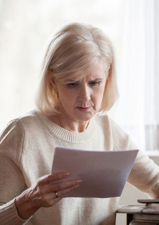 Woman looking at forms while typing on laptop